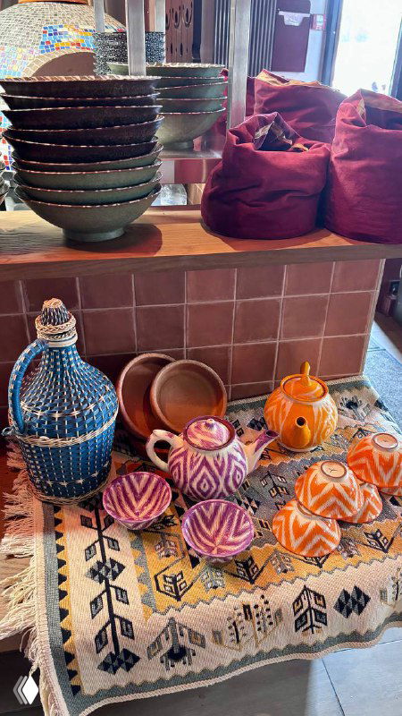 Полка с разноцветной керамикой и тканями в интерьере Kilim: традиционные турецкие сосуды, декор и этнические элементы в зоне бара.