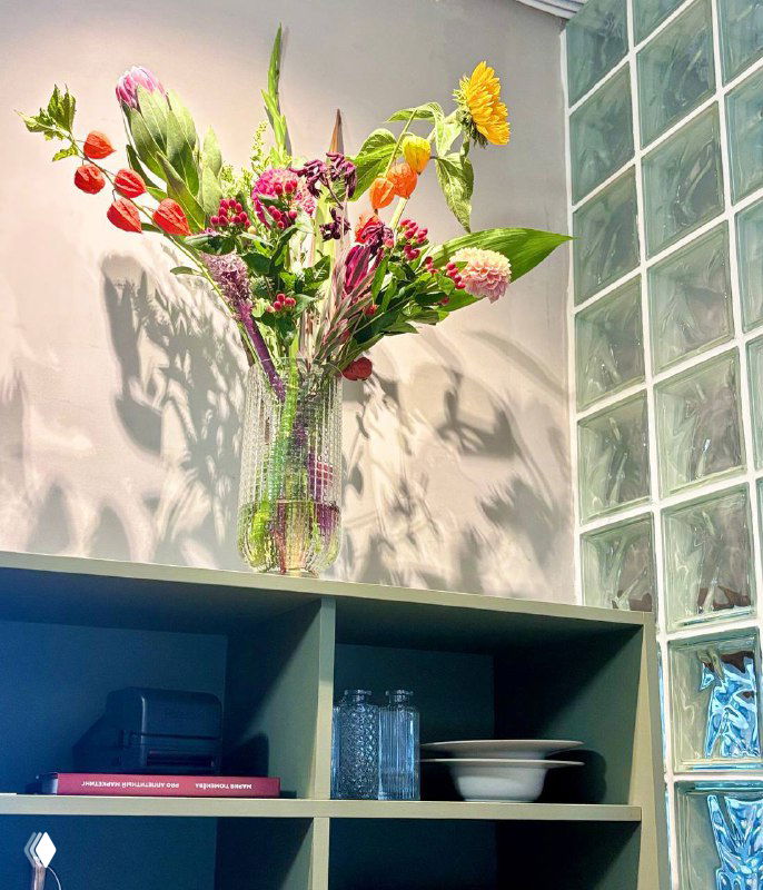 Ваза с весенними цветами на полке в интерьере Сentrale Bistro: мягкий свет, тень и декоративный акцент в уютном зале ресторана.