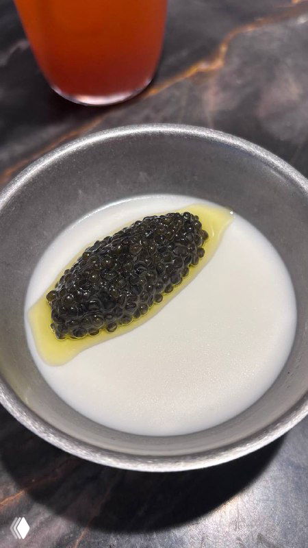 Небольшая миска с панна котой, на которой выложена осетровая икра и капля оливкового масла — контраст белой текстуры и чёрной икры.