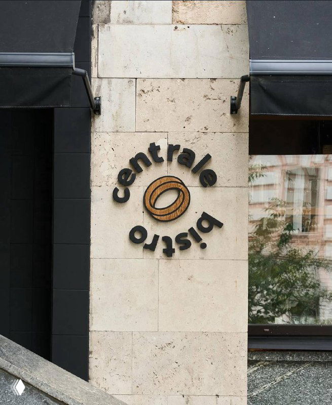 Фасад и вывеска Сentrale Bistro: логотип на светлом каменном фасаде, вход с витриной и уличным видом на Брюсов переулок.