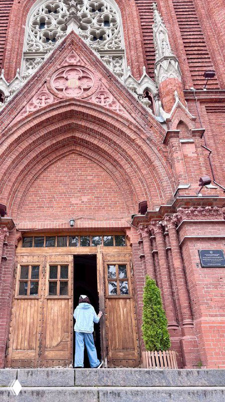 Входная группа собора: массивные деревянные двери, ступени и человек у порога, подчёркивающие масштабы Кафедрального Собора Непорочного Зачатия.