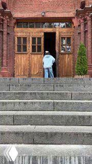 Подход к входу собора: широкая лестница, человек поднимается к деревянной двери, акцент на масштабе и доступности входной группы храма.