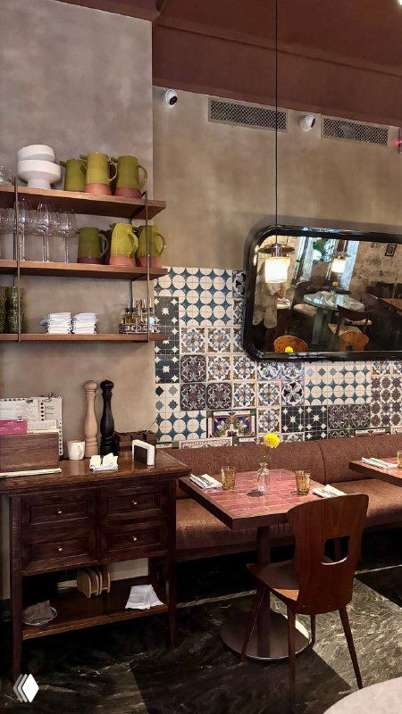 Уголок интерьера бистро с декоративными полками, зеркалом и плиточной стеной — детали оформления и атмосфера заведения.