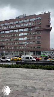 Фасад здания Наркомзема с улицы: многоэтажный корпус, припаркованные автомобили и тротуар на переднем плане, контекст городской застройки Москвы.