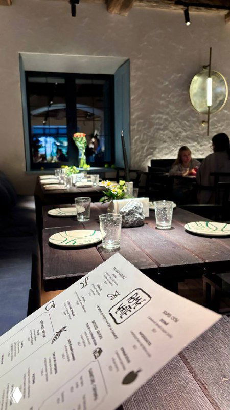 Панорамный кадр внутреннего зала с сервированными столами, скатертями и стеклянной посудой — спокойная вечерняя атмосфера ресторана.