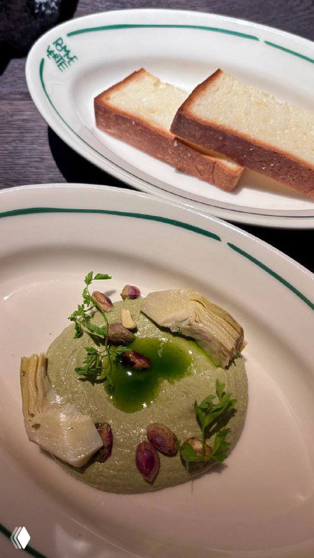 Тарелка с кремом из артишоков, фисташками и декором; снимок крупным планом демонстрирует текстуры и украшения блюда.