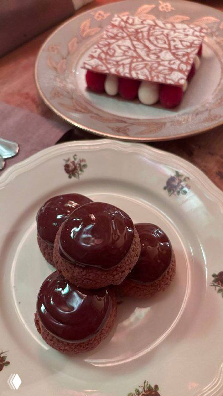 Блестящие шоколадные профитроли с ореховым кремом и шоколадным соусом, аккуратно выложенные на десертной тарелке — звезда вечера.