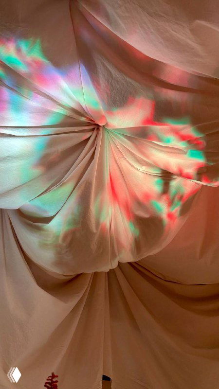 Тканевые драпировки потолка и цветные световые проекции в интерьере ресторана — атмосферный кадр оформления зала.