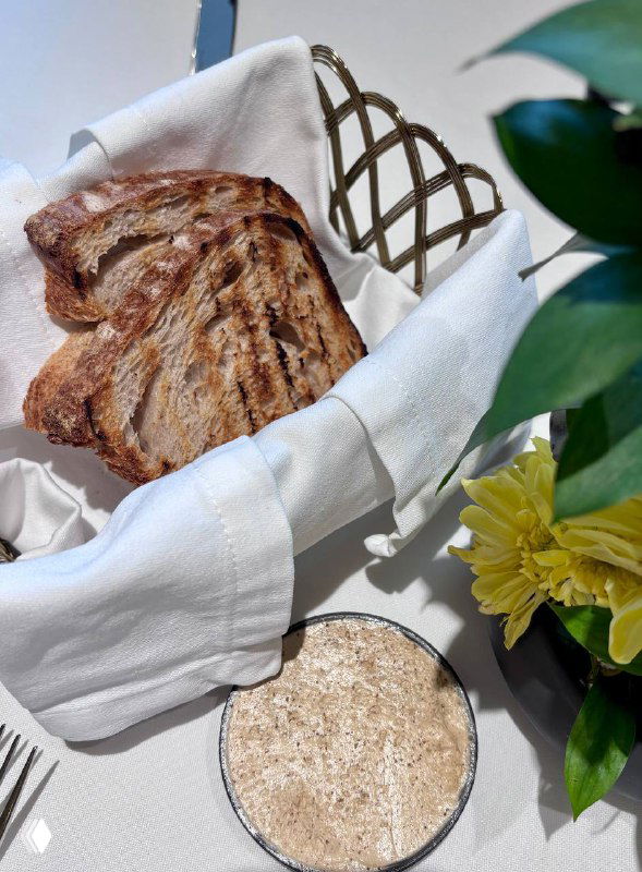 Корзинка с поджаренным хлебом и мисочка бородинского масла на скатерти — хлебный комплимент к подаче блюд в «Поле».