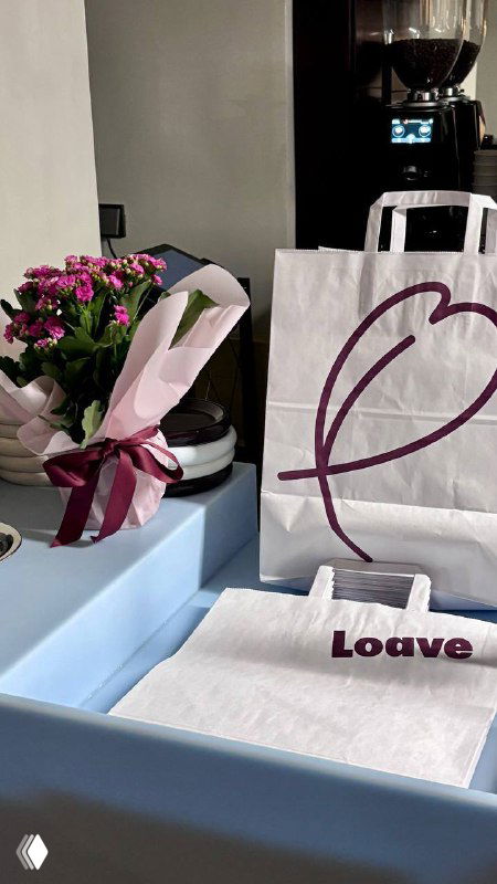 Пакеты и элементы фирменной упаковки Loave на прилавке: бумажные пакеты, цветы и минималистичная брендированная подача.