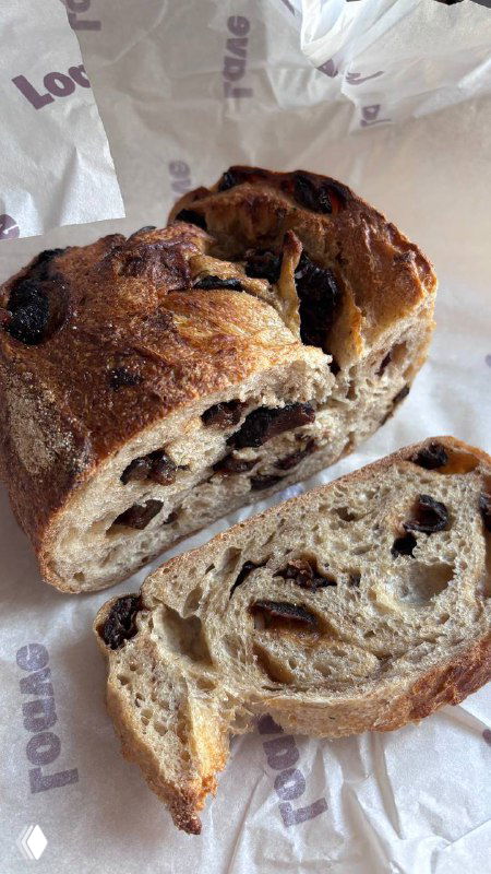 Разрезанный хлеб с черносливом: видно мякиш, кусочки чернослива и текстуру выпечки — демонстрация внутренней структуры буханки.