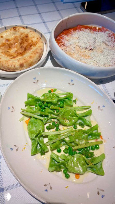 Тарелка с хрустящей зелёной спаржей и листьями салата на клетчатой хлопковой скатерти — кадр из греческого обеда в ресторане.