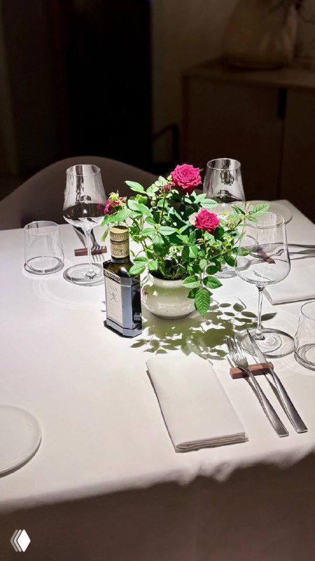 Центральный букет роз в вазе на сервированном столе, приборы и бутылки — фокус на цветочной композиции и оформлении стола в Luigi`s garden.