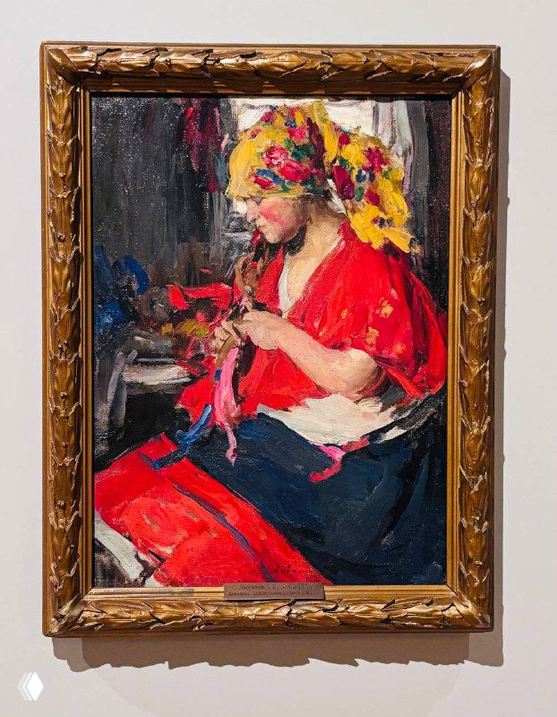 Женщина в красной рубашке и цветочном платке, занятая рукоделием; живописная фактура и золочёная рама, характерная для экспозиции.