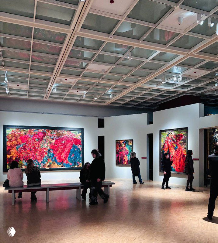 Зал Третьяковской галереи с посетителями перед большими картинами в красных тонах; скамьи и выставочное пространство дают представление о масштабе экспозиции.