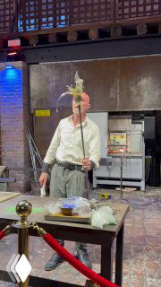 Мастер держит заготовку на металлическом жезле и показывает её посетителям, отображая процесс создания муранского стекла и демонстрацию для туристов.