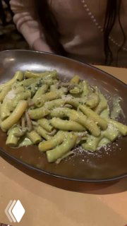 Тарелка пасты крупным планом, посыпанная тёртым сыром, текстура соуса и формы пасты видны на керамической тарелке в венецианском ресторане.