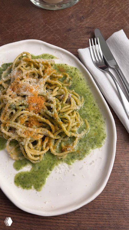 Тарелка спагетти с боттаргой на белой фарфоровой тарелке, зелёный соус по краю, видно крошки икры и подачу в стиле ресторана Рихтер.