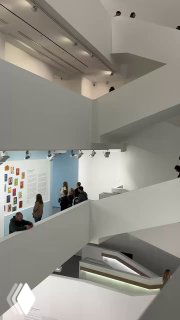 Вид на плавную внутреннюю лестницу и этажи белого интерьера Мультимедиа арт музея Москвы, посетители поднимаются между уровнями экспозиции.