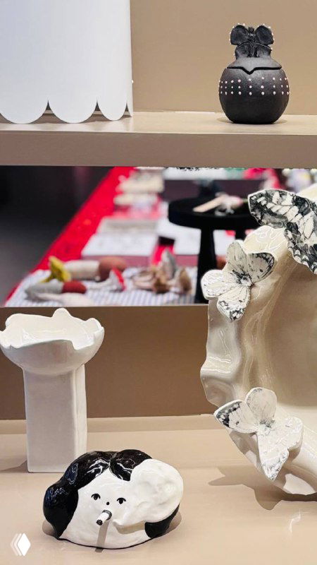 Набор керамических и декоративных объектов на полке: близкий ракурс показывает фактуры и форму изделий в выставочном пространстве.