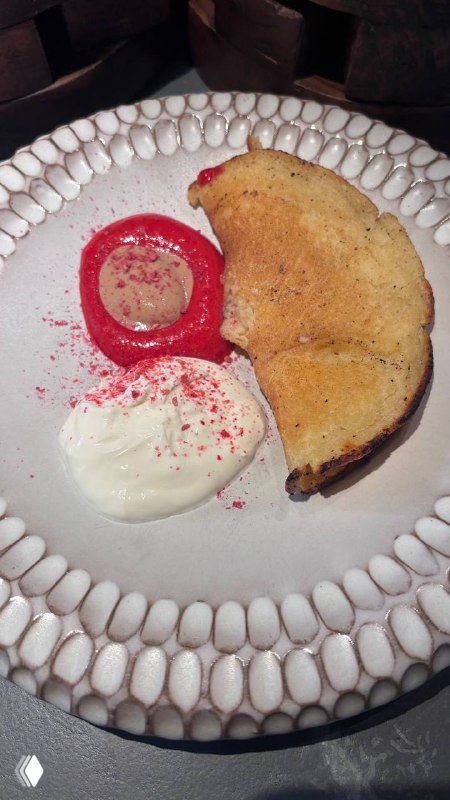 Блин из печи на белой тарелке с соусом и сливочным кремом, рядом розовое пюре или ягодный акцент, текстура и сервировка.