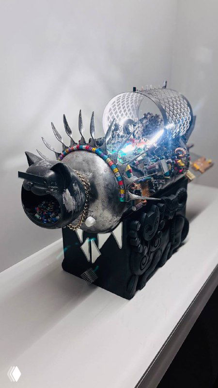 Металлическая скульптура в виде декоративного механического зверя, украшенная яркими деталями и зеркальными элементами под стеклом.