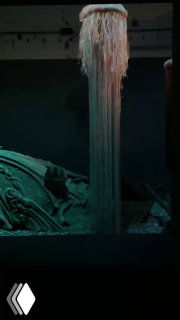 Тёмная сцена с висящими волокнистыми элементами, создающими эффект водной или органической массы внутри экспозиции.