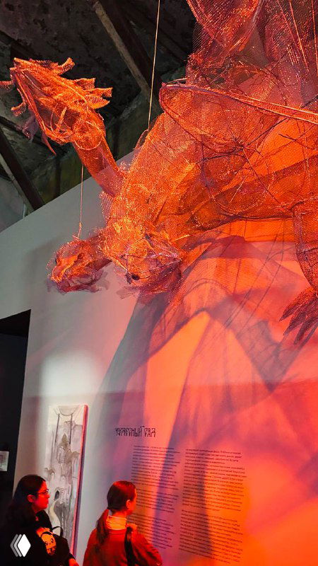 Полупрозрачная оранжево-красная тканевая или плетёная скульптура, подсвеченная изнутри, создающая драматический эффект в зале.