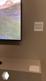 Экран с видеопроекцией и подписью рядом — часть мультимедийного стенда в выставке, минималистичное оформление стенда.