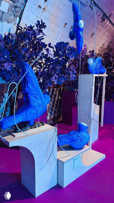 Композиция с синими скульптурными фигурами и архитектурными элементами на цветном подиуме — современный сценографический приём.