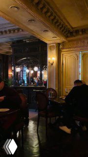 Общий вид зала ресторана с гостями, столами и зеркалами — тёплое освещение и классические мебель и люстры, атмосфера вечернего обеда.