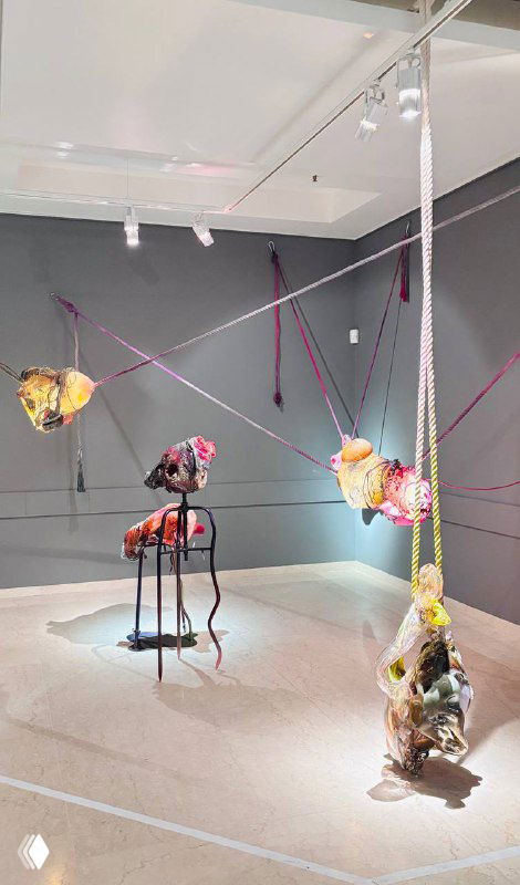 Инсталляция в зале Heritage: висящие и подвесные стеклянные объекты с цветными фрагментами и направленным светом, общий вид экспозиции.