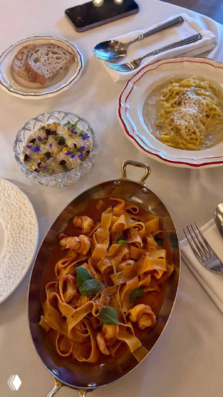 Вид сверху на сервированный стол в ресторане Шануар: тарелки с пастой, небольшие блюда, приборы и аккуратная белая скатерть, атмосферный кадр.