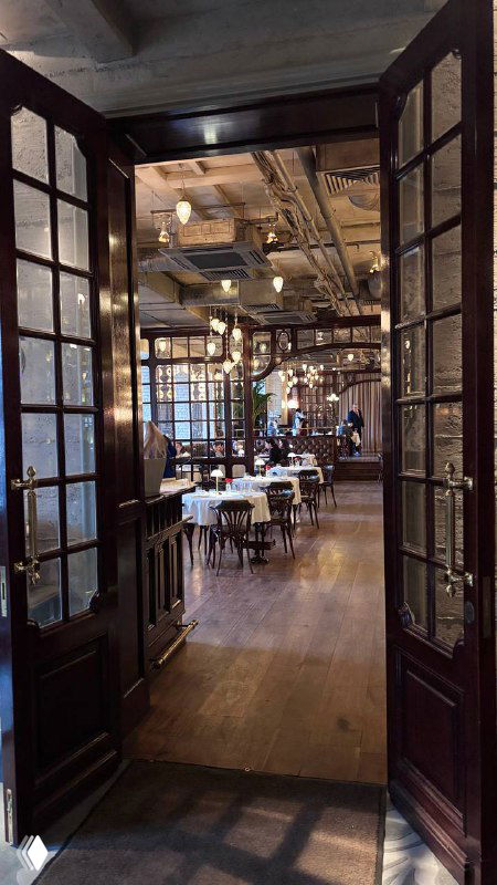 Вход в главный зал ресторана Шануар: двустворчатые двери открывают вид на зал с расставленными столами и элегантной классической атмосферой.