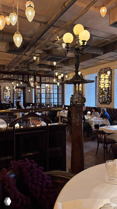 Интерьер одного из залов Шануар: круглые столы, кресла, старинные люстры и декоративные элементы — роскошная вечерняя атмосфера заведения.