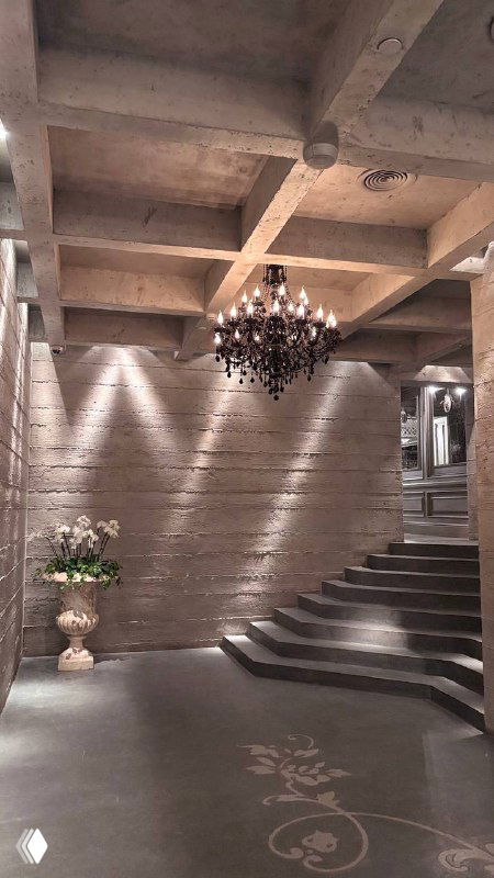 Лестничная зона внутри Шануар: ступени, бетонные потолки и сдержанная подсветка, интерьер с цветочной композицией у стены и атмосферой премиума.