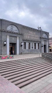 Фасад старого кинотеатра с широкими лестничными ступенями на фоне пасмурного неба, видно оформление входа и архитектурные детали здания