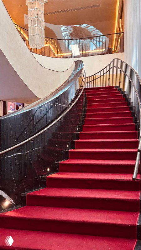 Внутренняя изящная лестница с красным ковровым покрытием и балюстрадой, создающая эффект ретро‑гламура в интерьере старого московского кинотеатра.