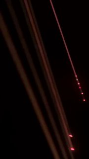 Тёмный кадр с диагональными лучами красного и жёлтого света, создающими эффект направленных световых дорожек в зале с лазерным шоу.