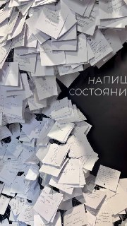 Стена, уставленная бумажными записками и посланиями посетителей — инсталляция с множеством вложенных листов и заметок от гостей.