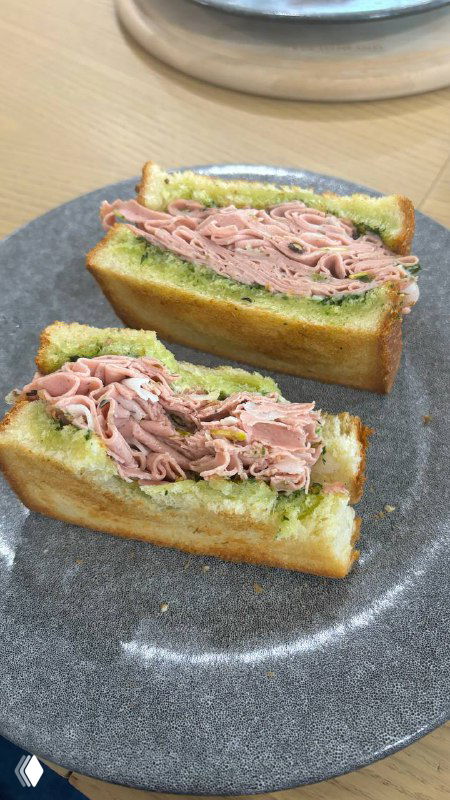 Разрезанный сэндвич с мартонадой или мартаделой, слои мяса и поджаренного хлеба хорошо видны на серой тарелке, минималистичная подача.