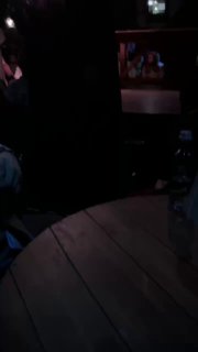 Часть круглого сценического пространства и столика в тёмном углу, на заднем плане видны зрители и отражения света.