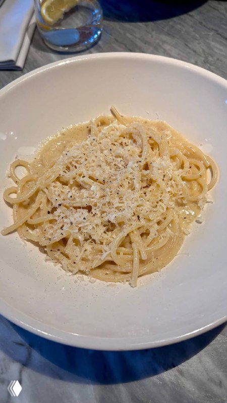 Тарелка со спагетти качо э пепе: паста с кремовым сырным соусом и перцем, сервировка в белой глубокой тарелке.