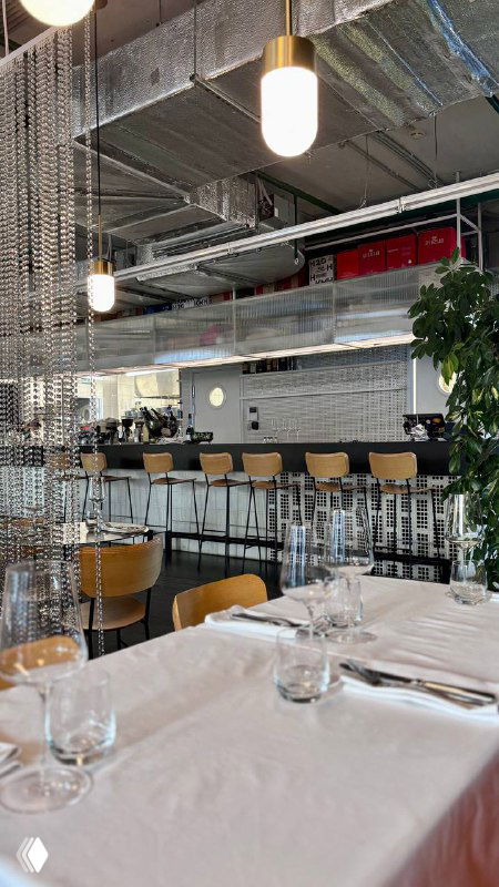 Интерьер ресторана КМ20: барная зона со стульями, цепочные шторы и освещение в индустриальном стиле, вид внутри заведения.