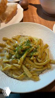 Теплая паста казаречче с кремовым соусом, горгонзолой и перцем на белой тарелке на деревянном столе в ресторане Rebecca.