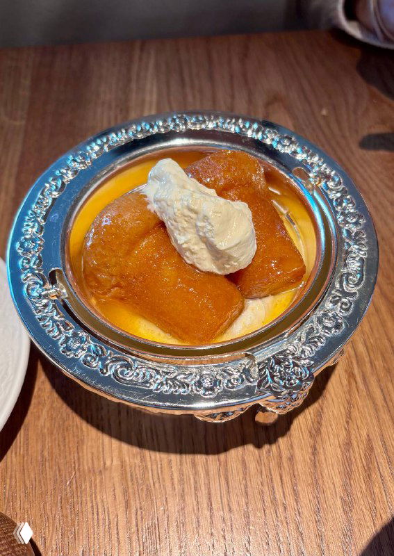 Ром-баба в серебряной пиале с кремовой отдушкой и аккуратной подачей, десерт на соседнем столе в ресторане Rebecca.