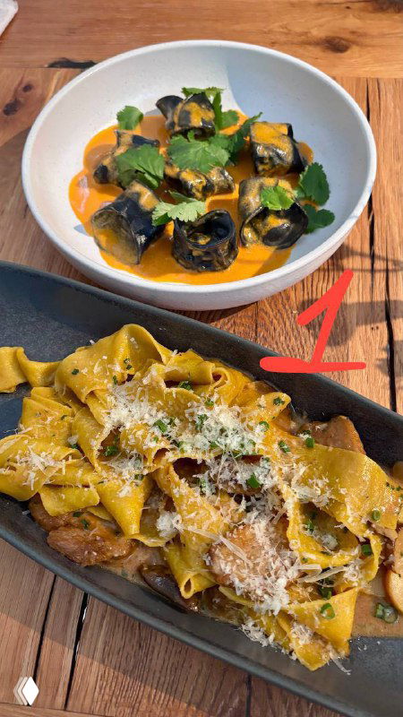 Тарелка с широкой лентой пасты, соусом и зелёными листьями как украшение — паста №1 в подборке московских ресторанов, вид крупным планом.