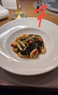 Фото пасты №7: белая тарелка с темной пастой или рисом и морепродуктами, подача минималистична, видно контрастные цвета ингредиентов.