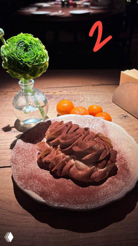 Тирамису с воздушным кремом на тарелке, рядом декоративный цветок и сыр, снимок из обзора ресторанных десертов в Москве.