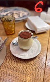 Стеклянный маленький стаканчик с тирамису, сверху посыпка какао, сервировка на деревянном столе с винтажной атмосферой.